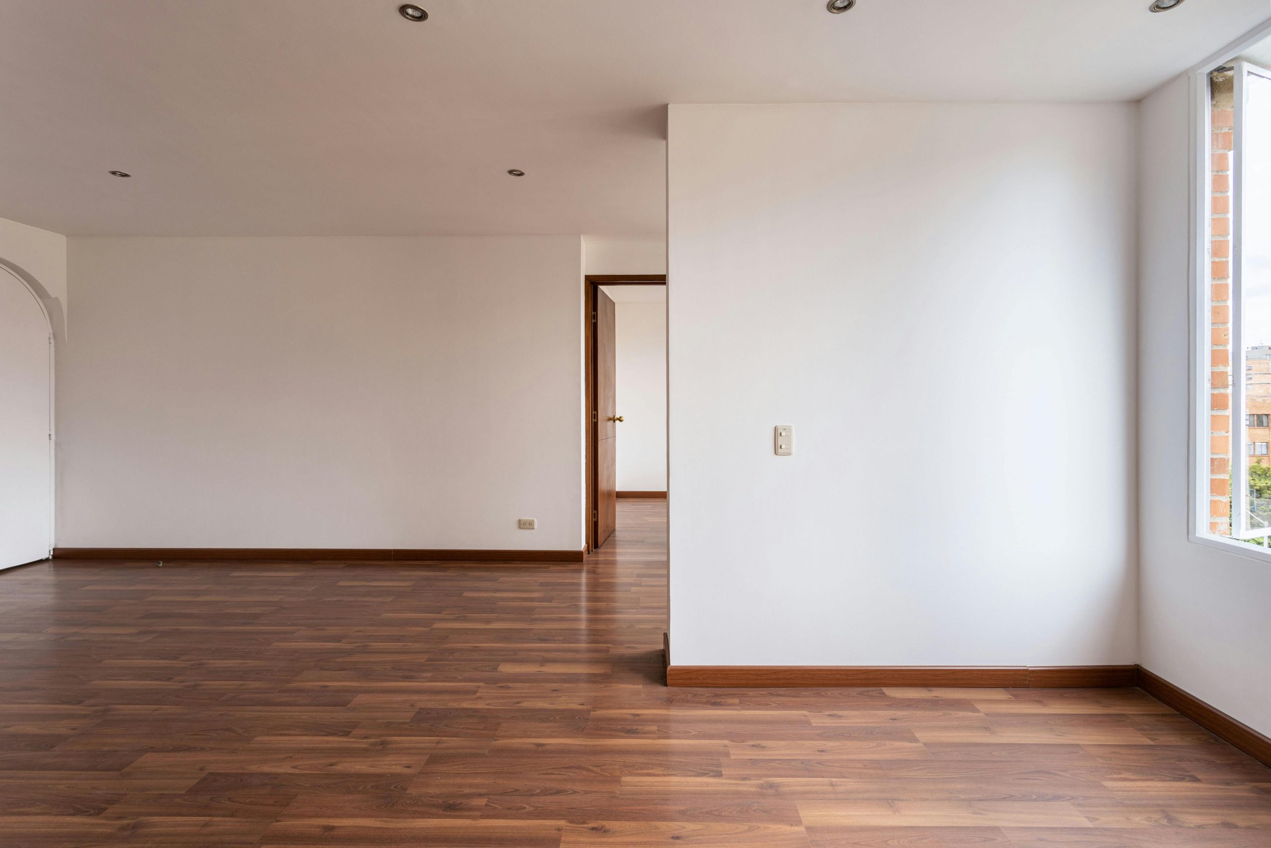Empty room with wooden floors and white walls, ideal for real estate or interior design concepts.